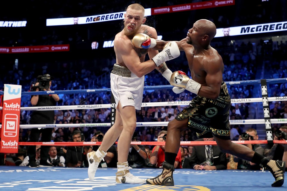 Floyd Mayweather Jr. throwing a punch at Conor McGregor during a boxing match.