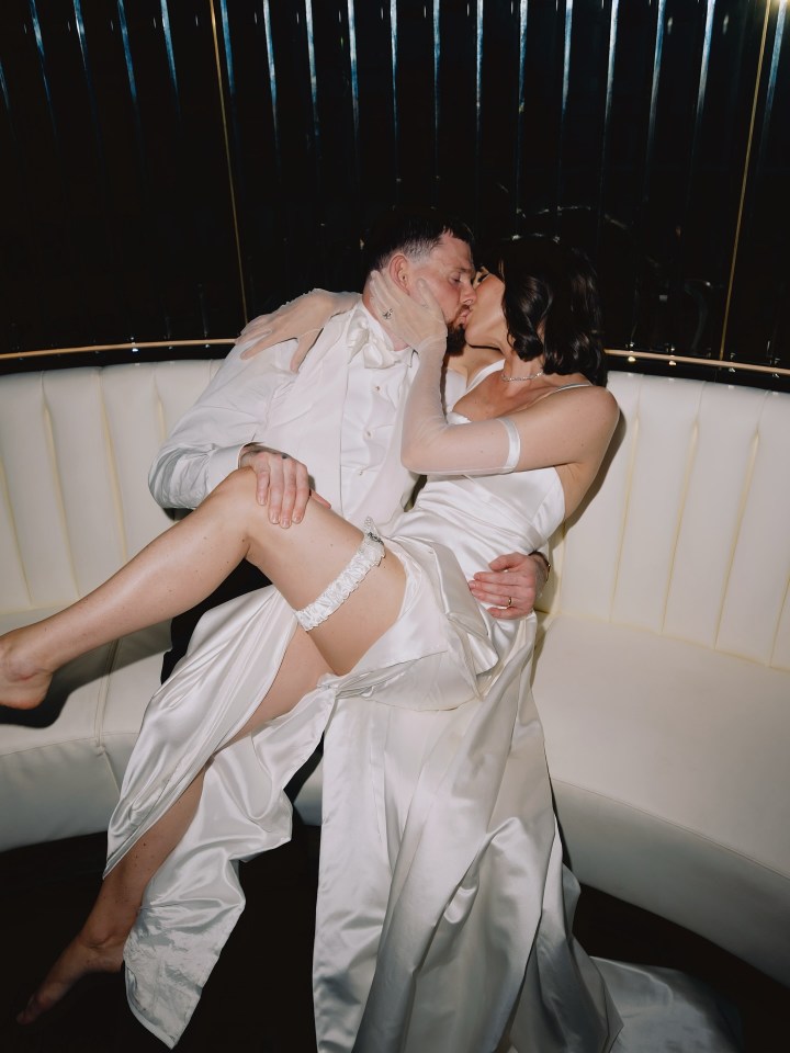 A bride and groom kissing on a white couch.