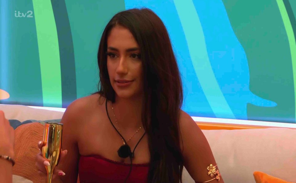 Shakira from Love Island holding a champagne flute.