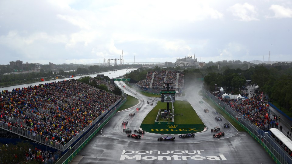 Overhead view of Formula One race cars navigating a hairpin turn in the rain.