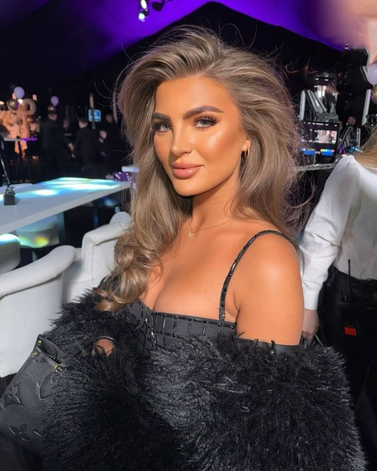 Portrait of a woman with long brown hair wearing a black dress and fur coat.