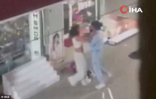 The pair grapple with each other outside a shop
