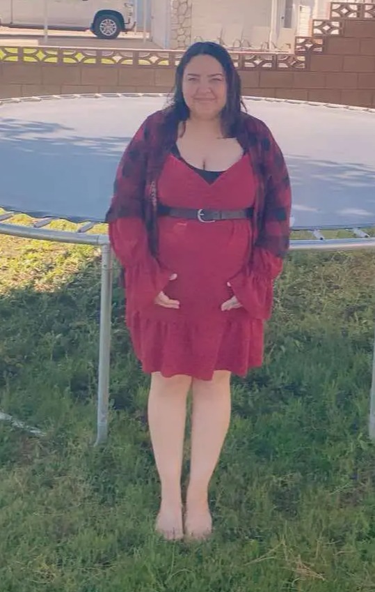 Pregnant woman standing in front of a trampoline.
