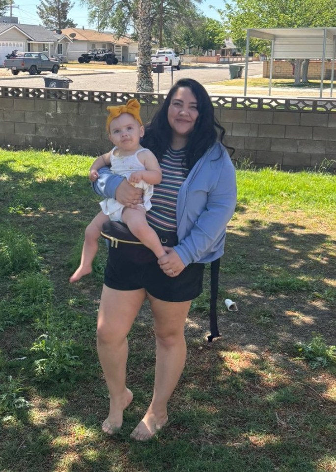 Woman holding baby in backyard.