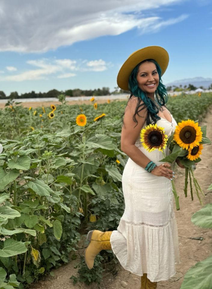 Woman in a sunflower field holding sunflowers.