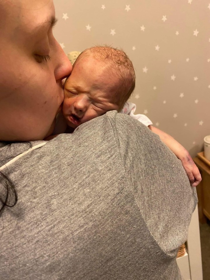 A mother kissing her newborn baby.