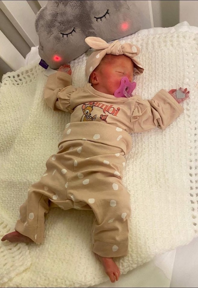 Newborn baby girl sleeping in polka dot outfit.