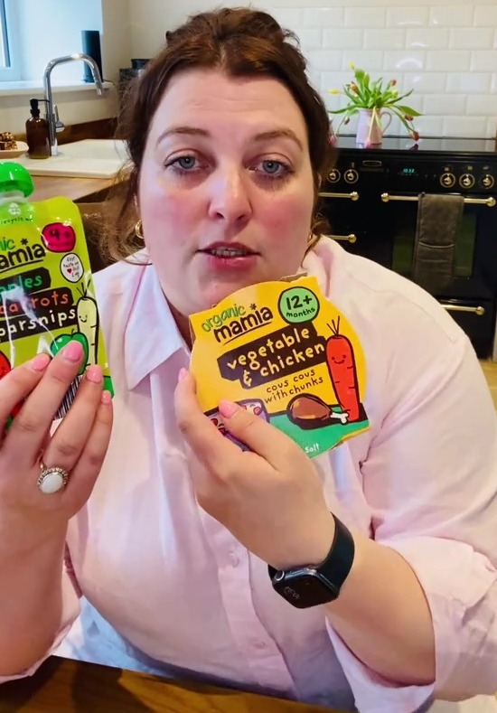 Woman holding two baby food pouches.