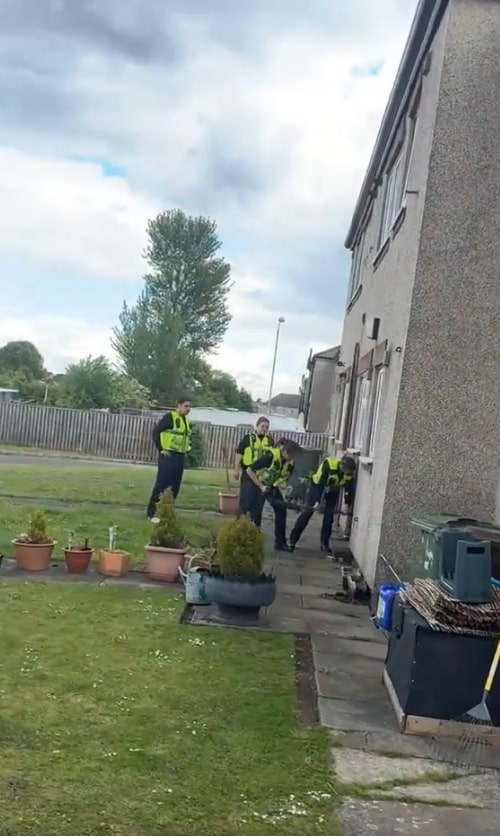 Police officers struggling to break down a door.