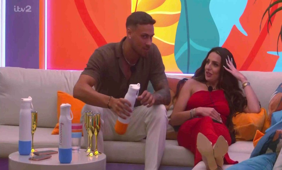 A man and woman sit on a couch and talk.