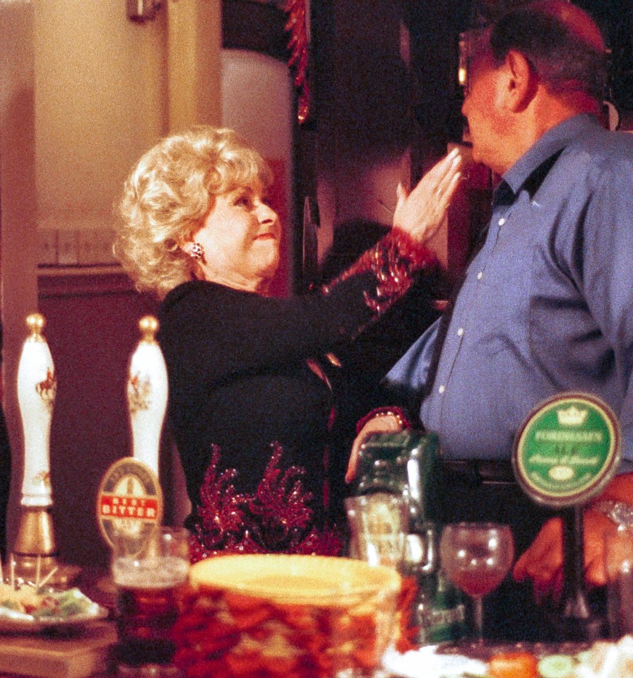 Scene from EastEnders featuring Pat Evans, Peggy Mitchell, and Frank Butcher in a pub.