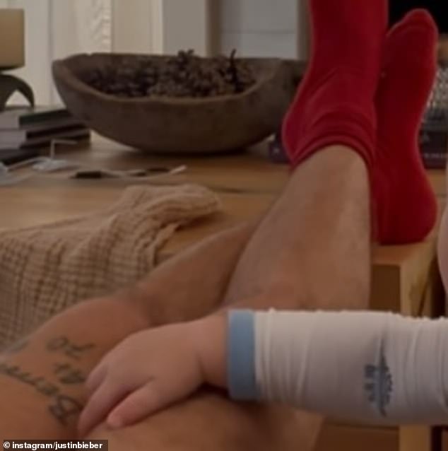 Amid pushback, Justin shared a sweet snap on Tuesday of the little one touching his leg while relaxing at home. 'Button for worry about yourself gramps,' responded a fan