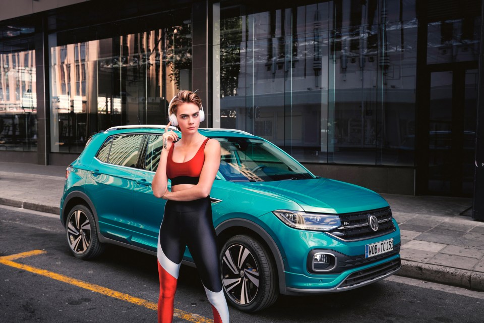 Cara Delevingne standing next to a teal Volkswagen T-Cross.