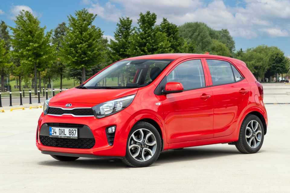 Red Kia Picanto city car parked outdoors.
