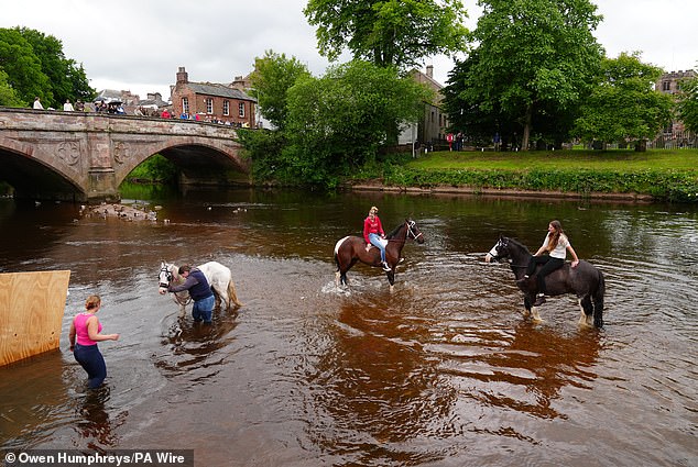 People riding horses in water during the Appleby Horse Fair in Cumbria on Sunday