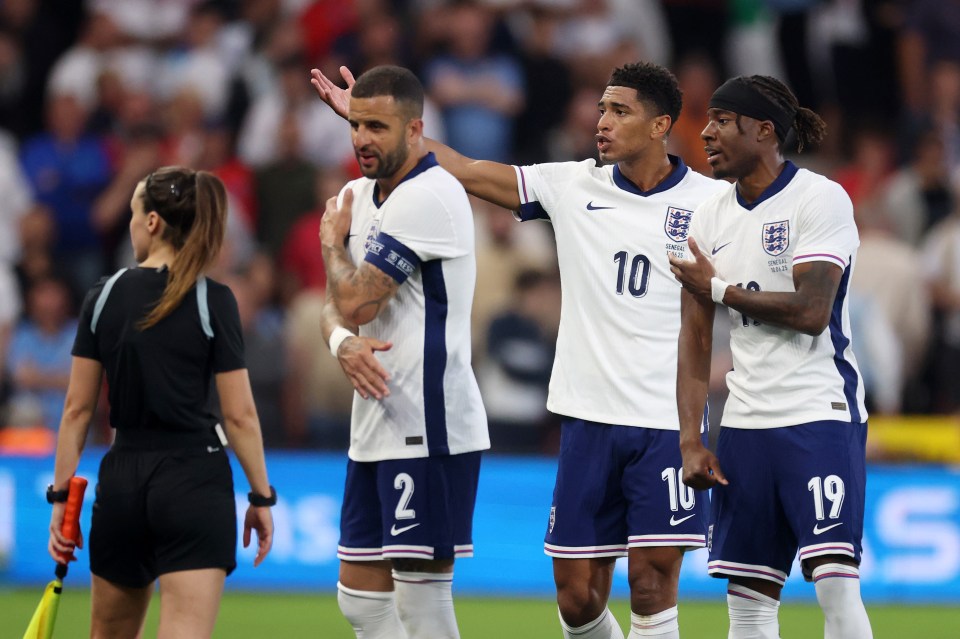 Kyle Walker, Jude Bellingham, and Noni Madueke of England react to an assistant referee during a soccer match.