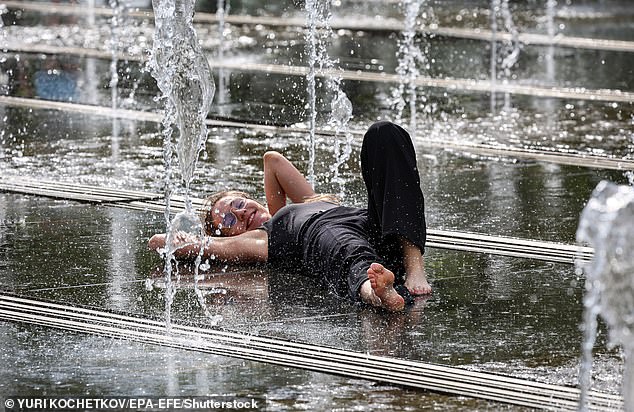 A young woman cools off amongst the water jets of a fountain during a hot spring day in Moscow, Russia, 26 May 2025