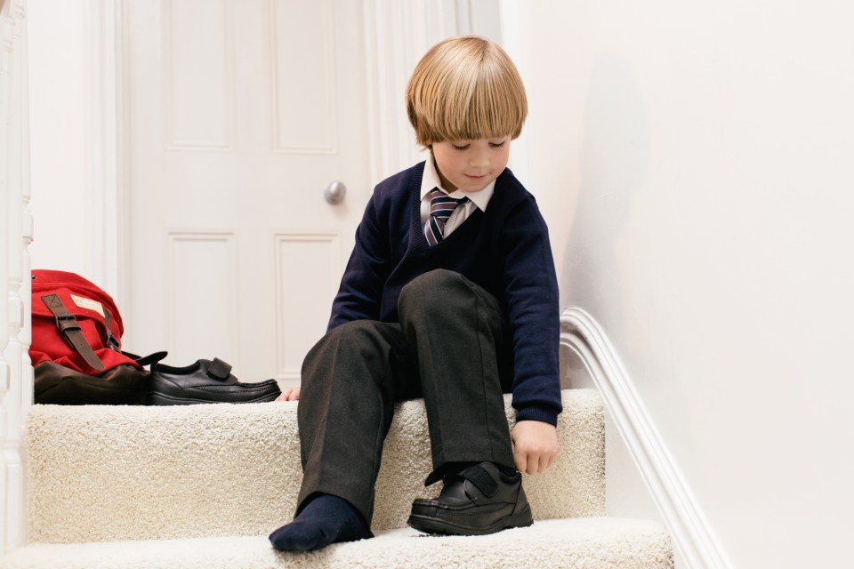 Boy in school uniform putting on shoes.