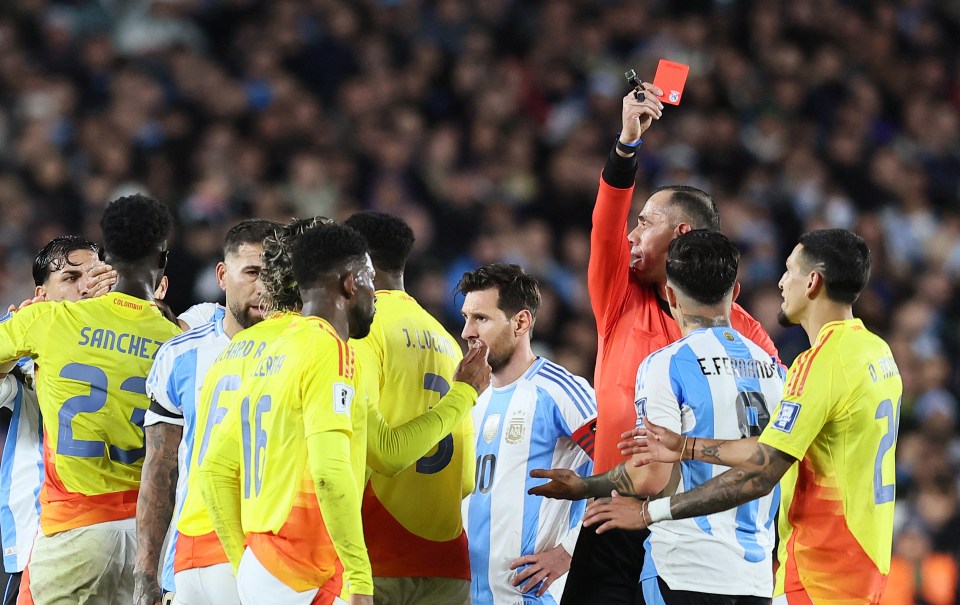 Referee showing a red card to Enzo Fernandez during a soccer match.