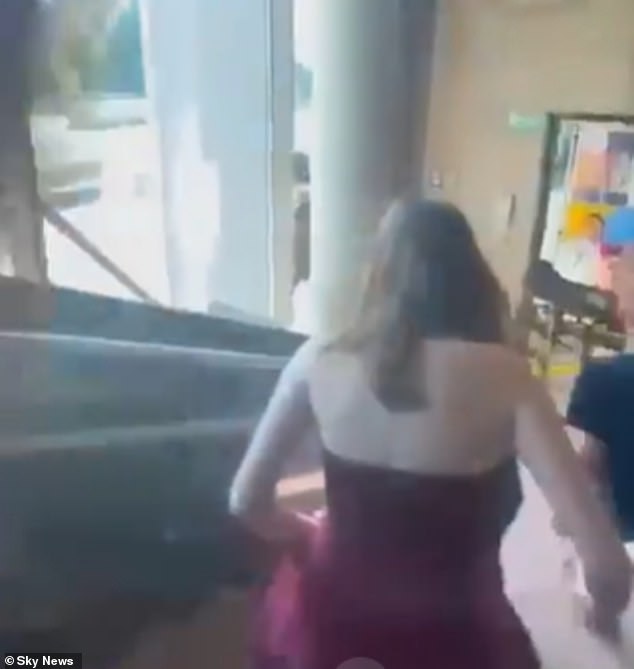 Pictured: Two female students cling on to each other as they escape the school building