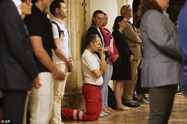 A member of rescue services knees on the floor and pray during a memorial service foloowing the shooting on June 10