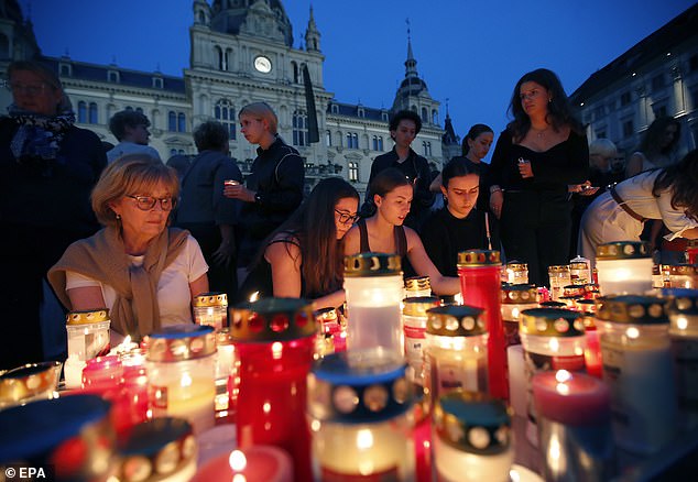 People light candles for the victims of a school shooting at Hauptplatz square in Graz, Austria