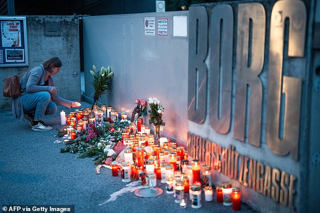 A woman leaves a candle at a makeshift memorial site near BORG Dreierschuetzengasse high school where the shooting took place