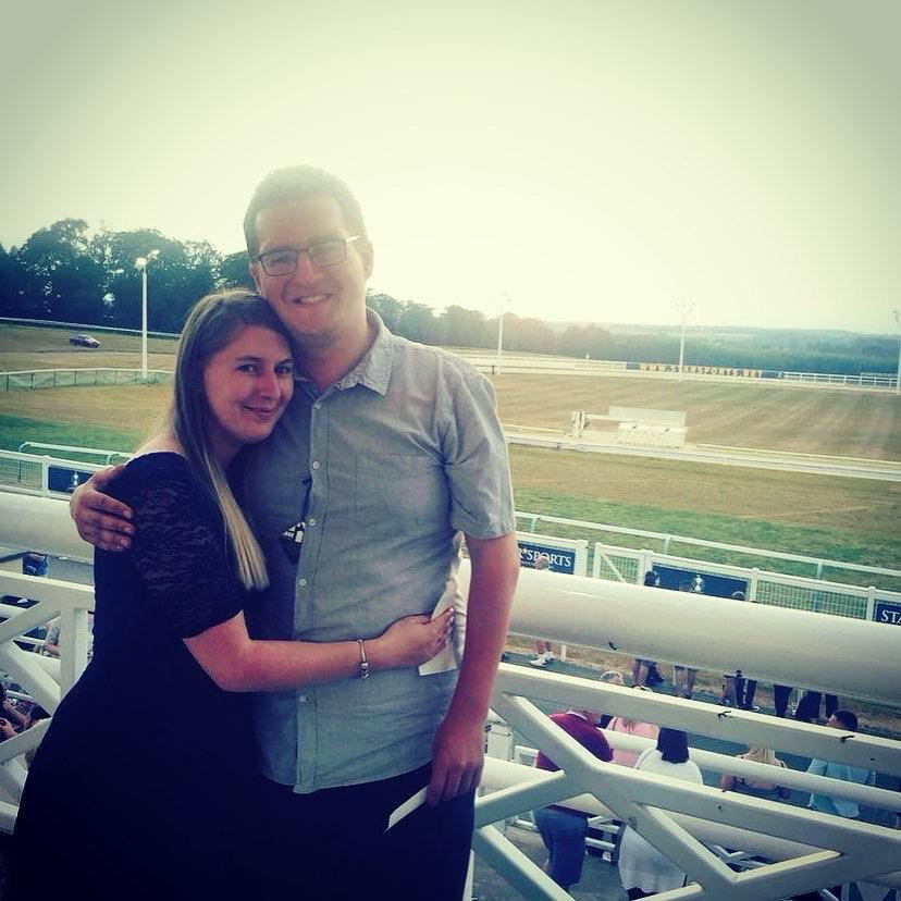 Photo of a couple embracing at a racetrack.