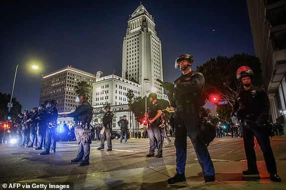 Los Angeles Metro Police officers stand on the road in front of the City Hall after a curfew was put into effect following days of protests in response to federal immigration operations in Los Angeles on June 10, 2025. Los Angeles police began arresting people in the city's downtown late on June 10, as groups gathered in violation of an overnight curfew after a fifth day of protests against Donald Trump's immigration crackdown. (Photo by Apu GOMES / AFP) (Photo by APU GOMES/AFP via Getty Images)