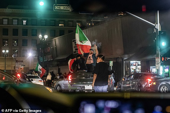 Demonstrators with Mexico flags ride a pick up truck on a street in downtown after curfew was put into effect following days of protests in response to federal immigration operations in Los Angeles on June 10, 2025. Los Angeles police began arresting people in the city's downtown late on June 10, as groups gathered in violation of an overnight curfew after a fifth day of protests against Donald Trump's immigration crackdown. (Photo by Apu GOMES / AFP) (Photo by APU GOMES/AFP via Getty Images)