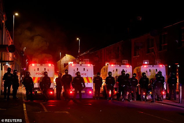 Officers line up in front of a burning vehicle during a second night of riots in Ballymena
