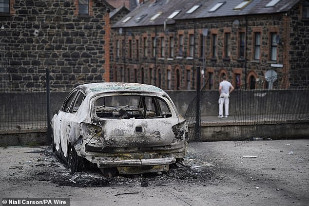 A burnt-out car on the street this morning following a second night of violence in Ballymena