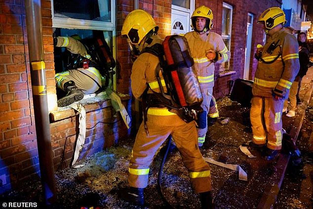 Firefighters get into a house where the windows have been smashed after demonstrators tried to enter
