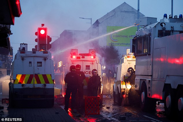 A water cannon is used as police officers stand guard during a second night of riots in Ballymena