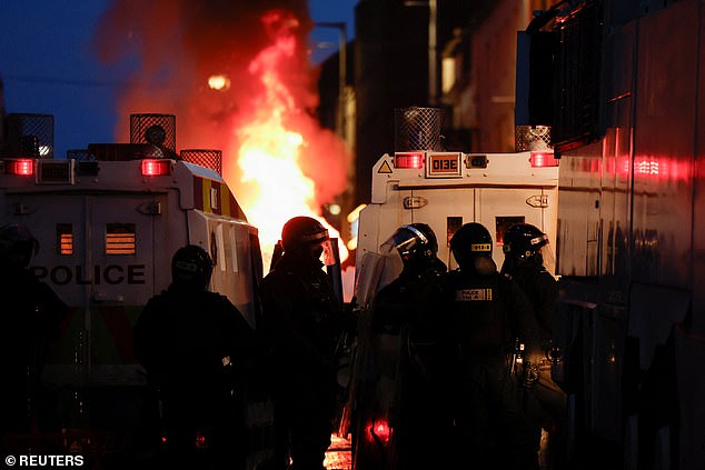 Riot police clash with masked yobs in Ballymena, Northern Ireland, on Tuesday night during a protest over an alleged sexual assault