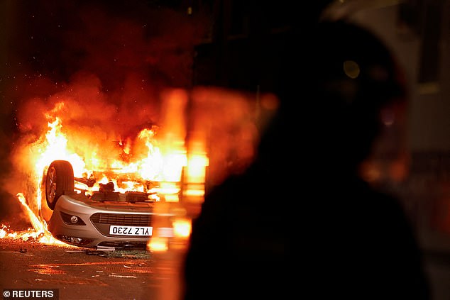 A car is set on fire and tipped upside down in Ballymena on Tuesday night amid the chaos