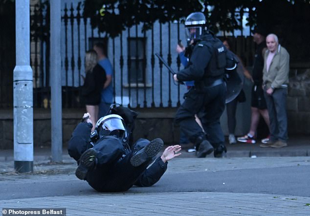 A police officer falls to the ground during Tuesday's riots in Northern Ireland