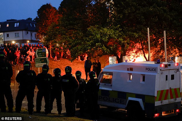 Police officers stand guard as they clash with masked yobs during day two of demonstrations