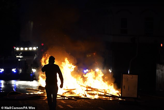 A person walks among the fire created during the demonstration over an alleged sexual assault