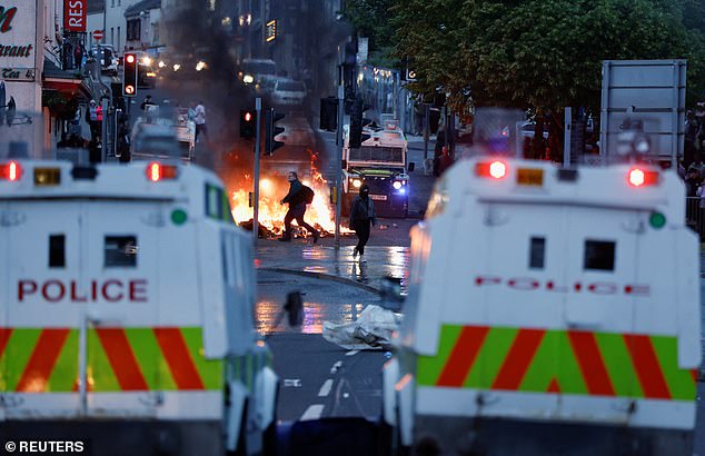 People run among the flames in Ballymena on Tuesday during the second evening of chaos