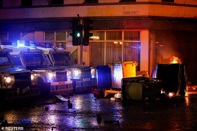 Police vehicles are parked in a line forming a wall, seemingly to stop crowds getting through