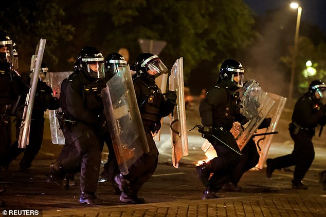 Riot police run through the town with their armour as they try to control the crowd