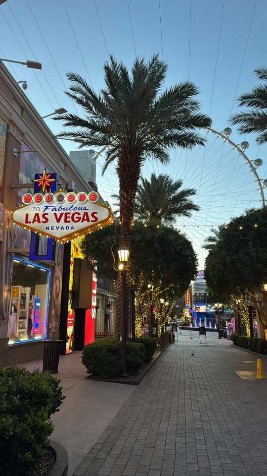 Las Vegas welcome sign and High Roller observation wheel at dusk.