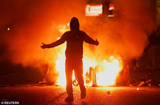 Fire burns near a demonstrator as riots continue in Ballymena, Northern Ireland, on Wednesday night