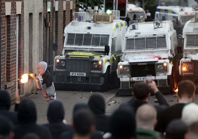 A person throws harmful objects at riot police vehicles in Ballymena last night