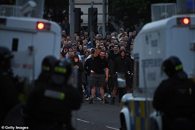 A man looks towards members of the PSNI riot squad stood next to their vehicles