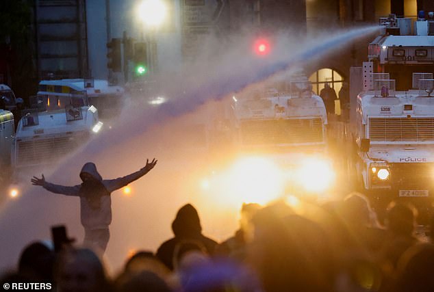 Police aim a water cannon at demonstrators as riots continue in Ballymena