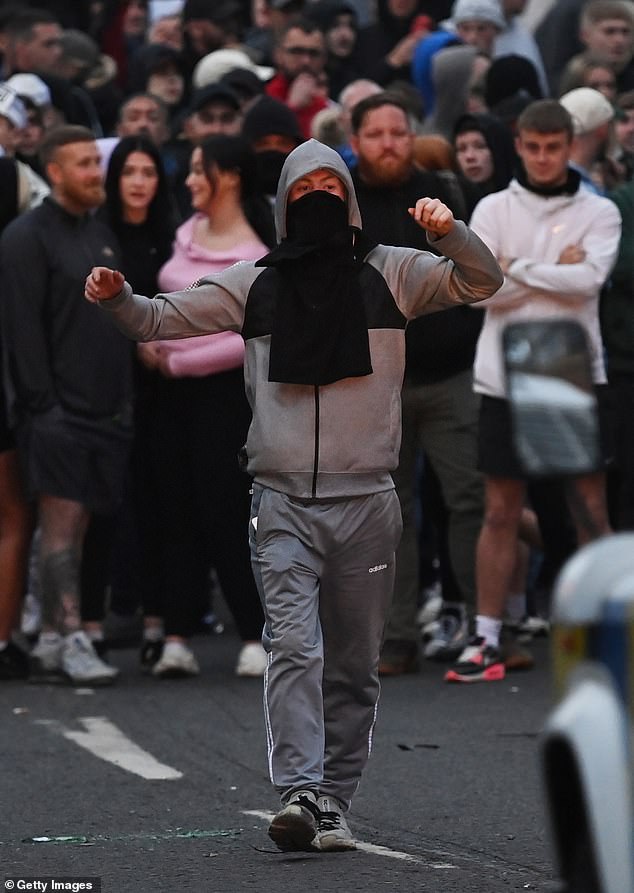 A member of the crowd gestures towards the PSNI riot squad officers in Ballymena