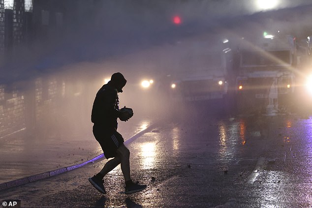 Protesters try to throw items at the police who use water canons to clear them in Ballymena
