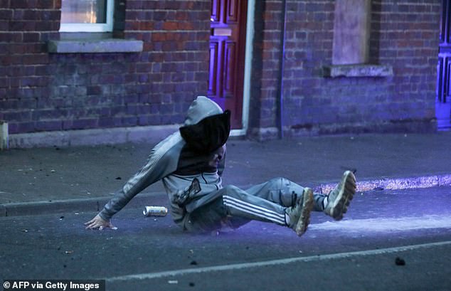 A masked protestor falls after being hit by the Police water cannon, used in an attempt to disperse protestors